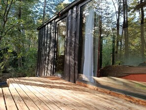 A wooden deck with a glass wall overlooking a forest. - Shinrin Lodge | River, forest, clay tub, breakfast, transportation. All-inclusive (Huililco)