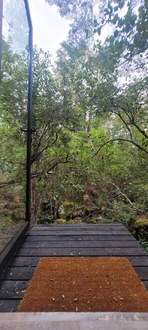 A wooden deck with a brown mat, surrounded by dense forest. - Shinrin Lodge | River, forest, clay tub, breakfast, transportation. All-inclusive (Huililco)