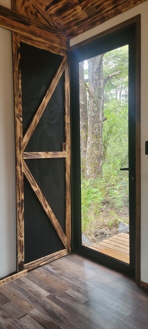 A room with a wooden door leading to an outdoor area with a view of trees and a wooden deck. - Shinrin Lodge | River, forest, clay tub, breakfast, transportation. All-inclusive (Huililco)