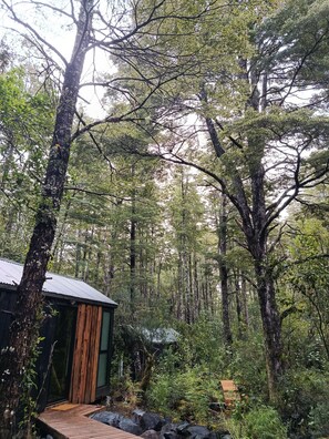A cabin with a wooden deck, surrounded by dense forest. - Shinrin Lodge | River, forest, clay tub, breakfast, transportation. All-inclusive (Huililco)