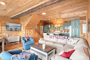 A cozy cabin interior with a living room, dining area, and kitchen.