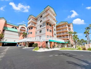 A multi-story hotel with a central atrium, balconies, and a covered entrance. - Ocean-View Oasis: 2BR Condo w/ Pool & Private Balcony (Indian Shores)