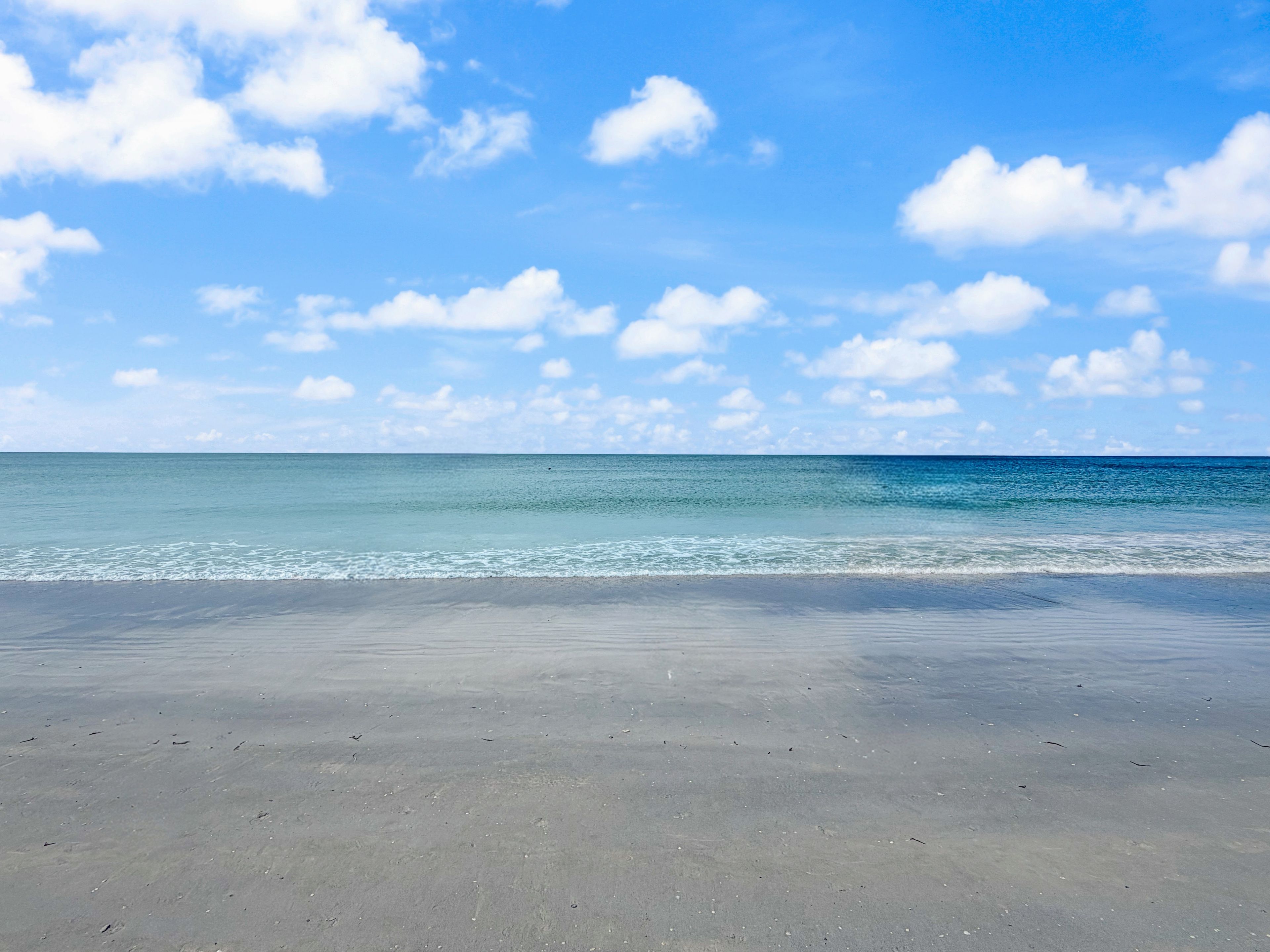 A beach with a clear sky and calm sea.