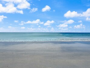 Une plage avec un ciel dégagé et une mer calme.