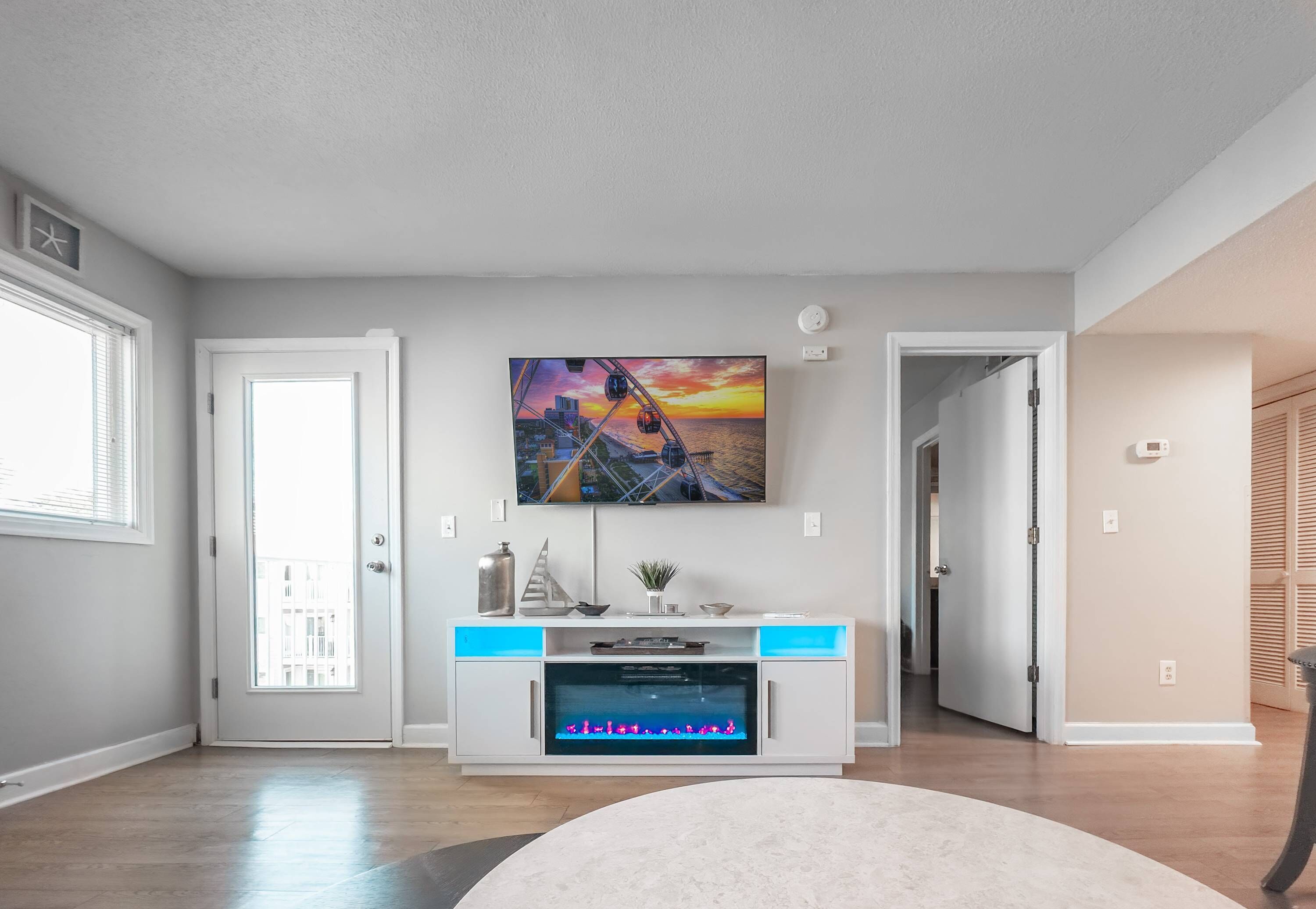 Een moderne woonkamer met een flatscreen televisie, een open haard en een groot raam.