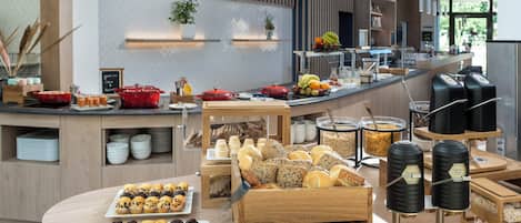 Zona de bufé con diversas opciones de comida, como pastelería, pan y frutas.