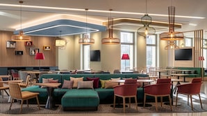 Een moderne lounge met zitplaatsen, tafels en sfeerverlichting.