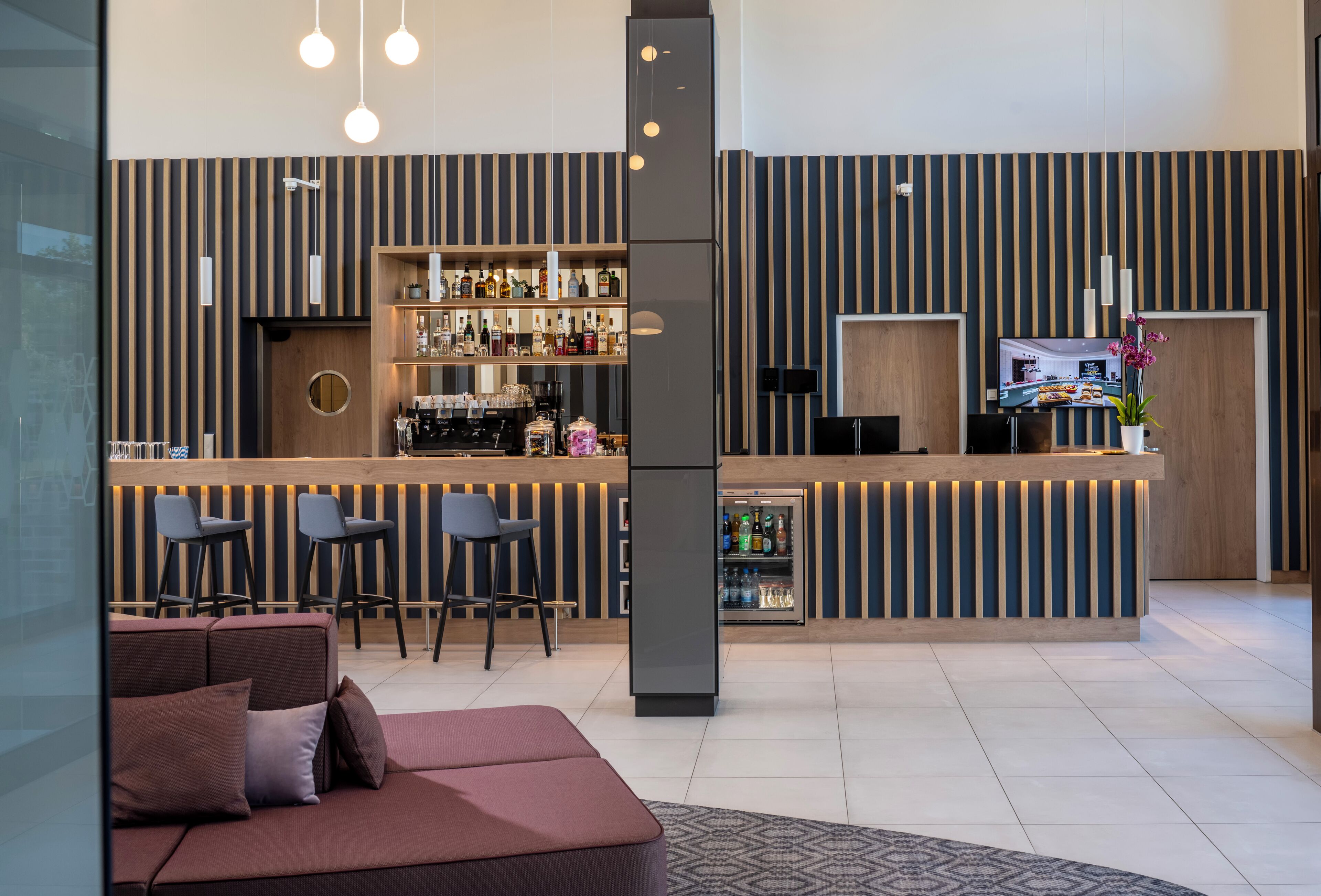 Un área de bar moderna con mostrador, taburetes y refrigerador.