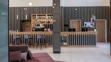 Un área de bar moderna con mostrador, taburetes y refrigerador.