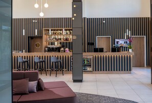 A modern bar area with a counter, stools, and a refrigerator. - Hampton By Hilton Bremen North (Bremen)