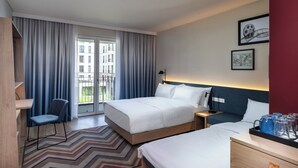 Hotelkamer met een groot bed, een kleiner bed, een bureau, een stoel en uitzicht op het omliggende gebied.