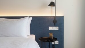 Een hotelkamer met een bed, nachtkastje, lamp en een stopcontact.
