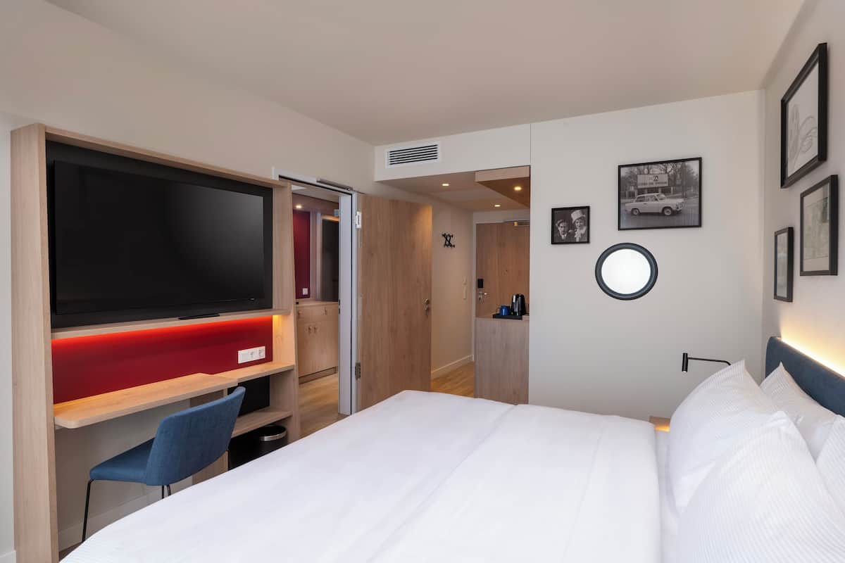 Habitación de hotel con cama, televisor, escritorio y silla.
