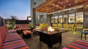 An outdoor seating area with a fire pit, yellow chairs, and a striped sofa. - Home2 Suites By Hilton Jacksonville Mayo Clinic Area (Jacksonville)