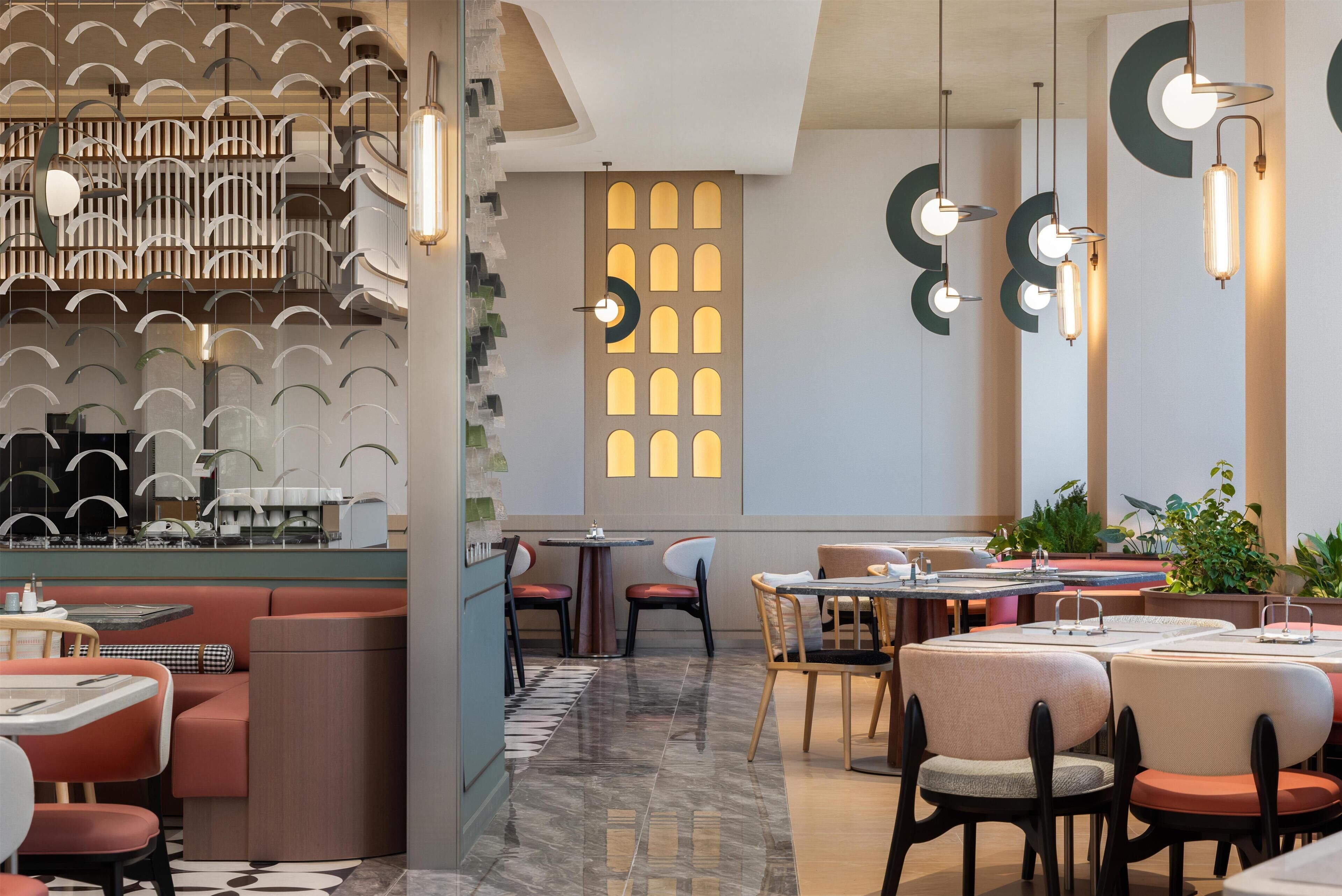 A modern restaurant interior with a bar area, seating arrangements, and decorative lighting.