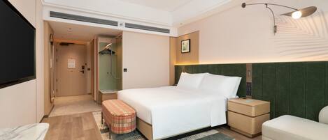 A hotel room with a bed, bedside tables, a TV, a walk-in closet, and a bathroom.