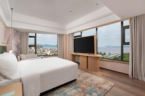 Una habitación de hotel moderna con una cama grande, televisión de pantalla plana y vistas a la ciudad.