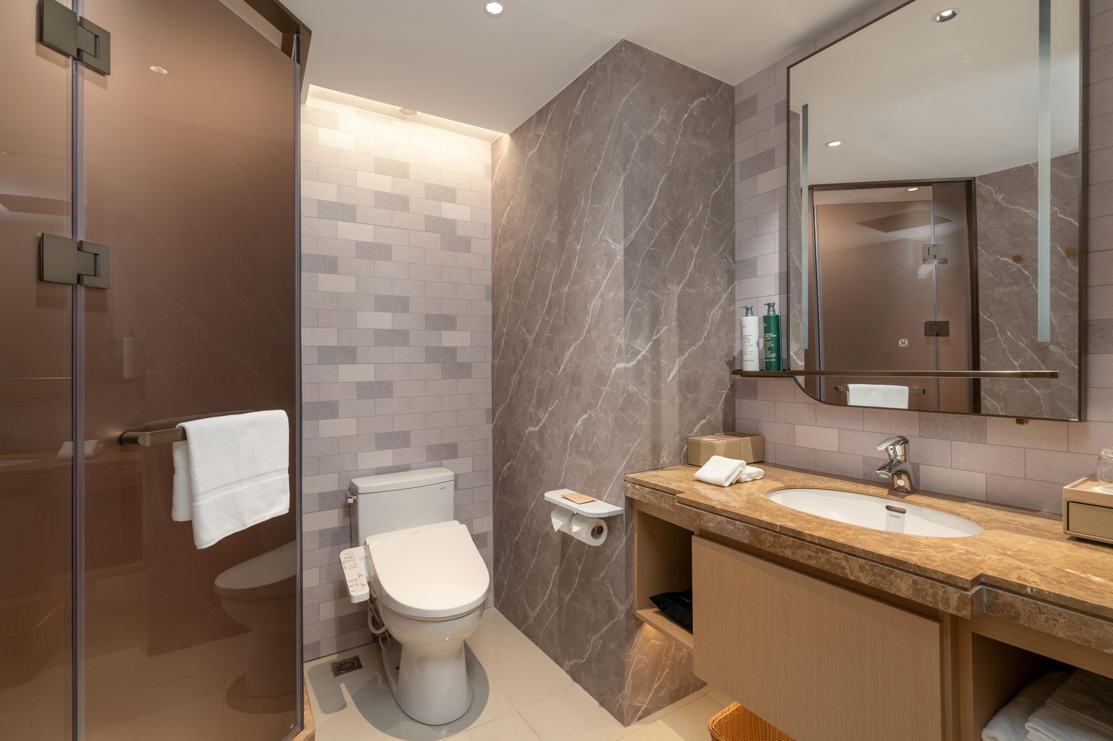 Une salle de bain moderne équipée de toilettes, d’un lavabo et d’un espace douche.