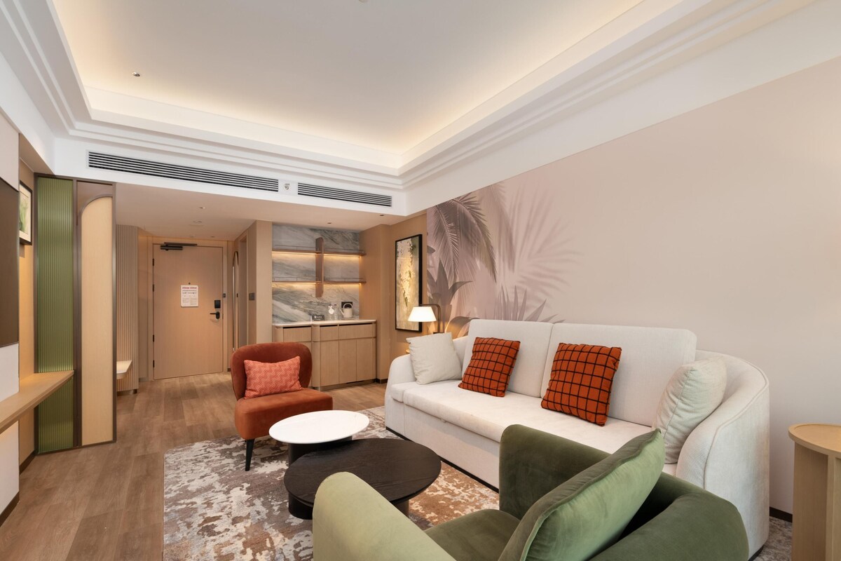 Una sala de estar moderna con un sofá, sillones, una mesa de centro y un amplio mural en la pared.
