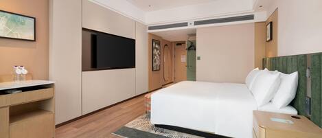 Una habitación de hotel con cama, escritorio, televisión de pantalla plana y puerta al baño.