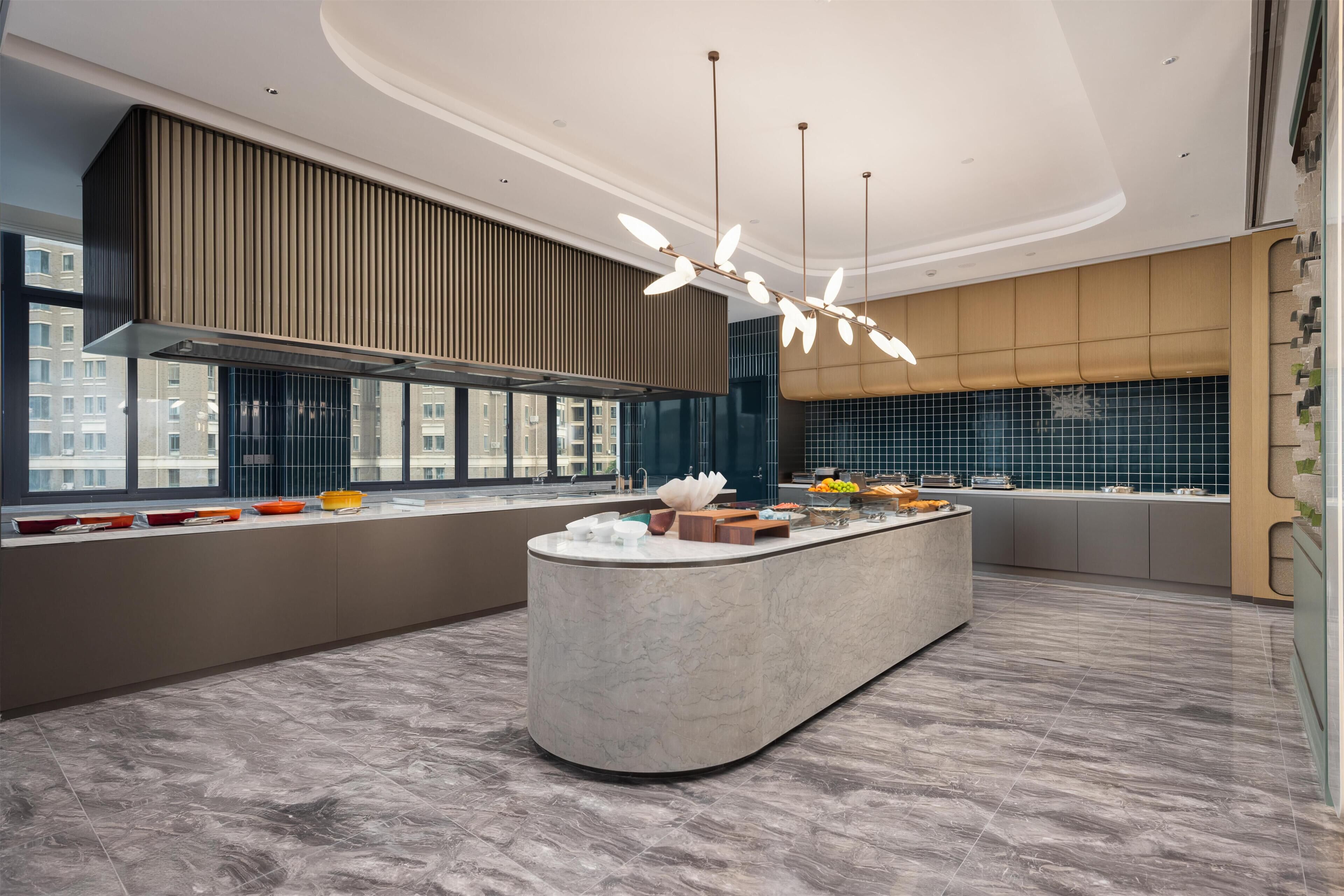A modern kitchen with a central island, large windows, and a view of the city.