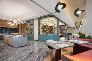A modern restaurant interior with a central island, seating area, and decorative lighting.