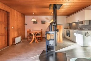 Eine moderne Küche mit Holzofen, weißen Schränken und einem Essbereich mit Holztisch und Stühlen.