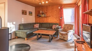 A cozy living room with a sectional sofa, a wooden coffee table, a small armchair, and a television. - Familienfreundlicher Doppelbungalow mit Terrasse in Mirow (Mirow)
