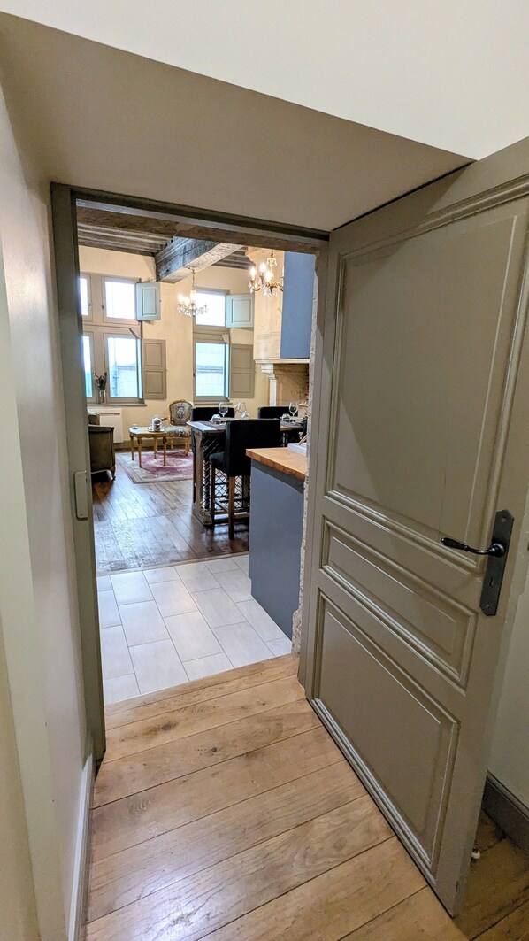 A hallway leading to a kitchen with wooden flooring, a bar area, and a dining setup.