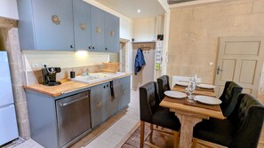 A compact kitchen with grey cabinets, a wooden countertop, and a dining area with a table set for four.