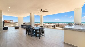 Ein geräumiger Balkon mit Essbereich, Deckenventilator und Blick auf den Ozean.