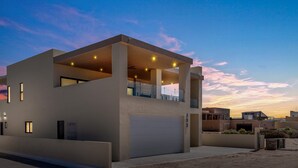 Ein modernes, zweistöckiges Haus mit Garage, großen Fenstern und einem Balkon.