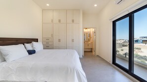 Ein Schlafzimmer mit einem großen Bett, einem Kleiderschrank und Blick durch ein Fenster.