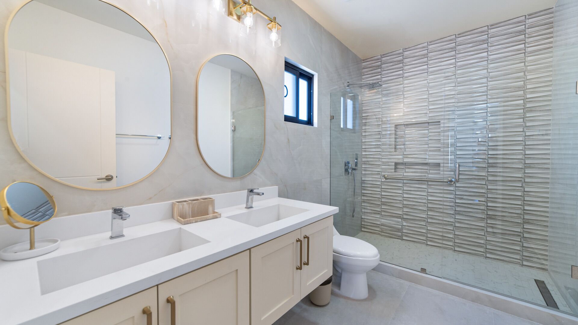 Une salle de bain moderne avec un meuble-lavabo à deux vasques, des toilettes et une douche séparée par une paroi en verre.