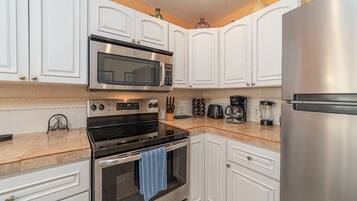 A kitchen with white cabinets, stainless steel appliances, and a marble countertop.