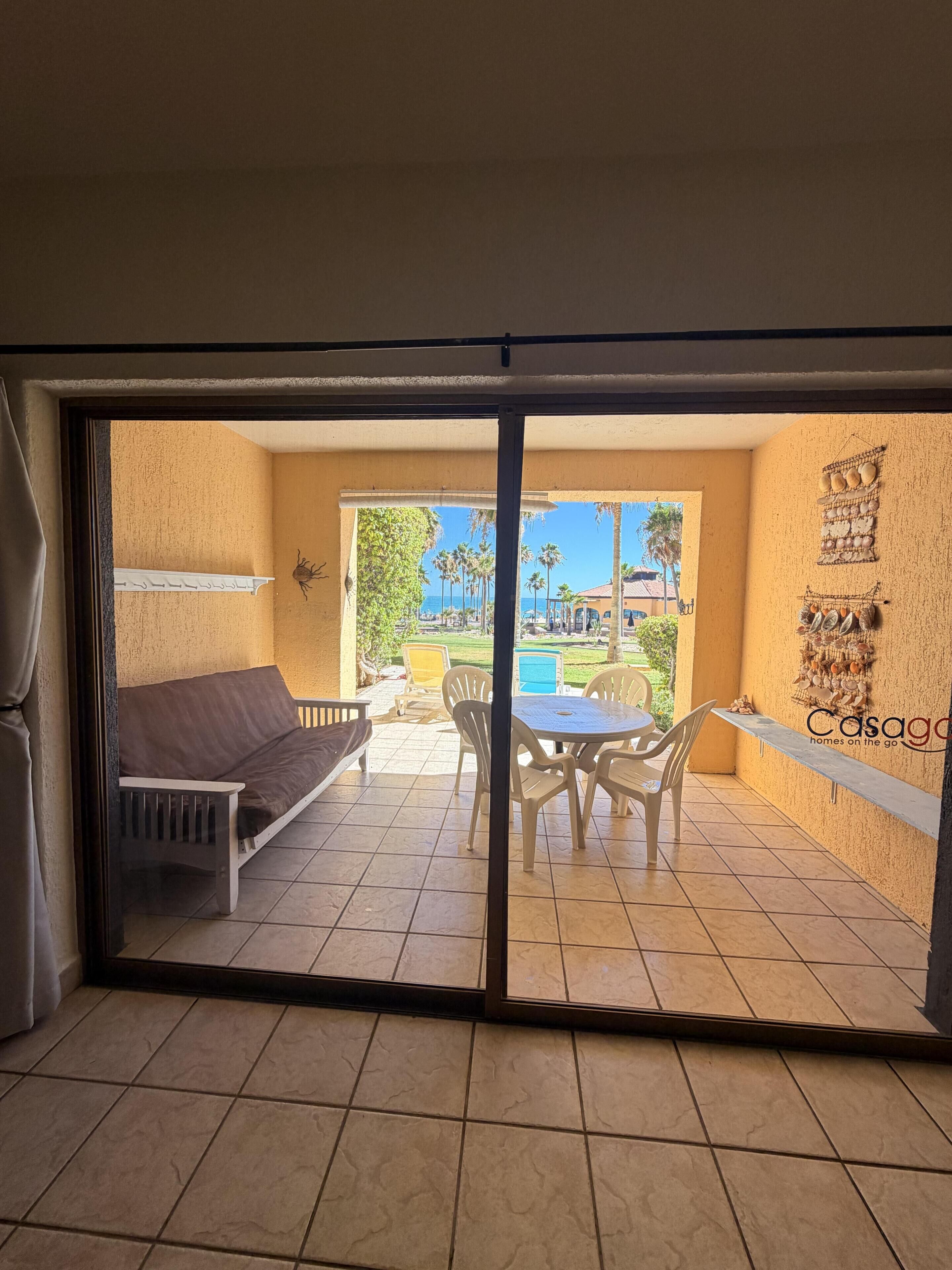 Ein Zimmer mit einer Schiebetür zu einem Außenbereich mit Pool, einem Tisch mit Stühlen und einer Sitzecke.