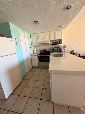 A kitchen with white cabinets, a stove, a microwave, and a sink. - Princesa Resort D-105 - A Ground Floor Ocean View Condo (Puerto Peñasco)