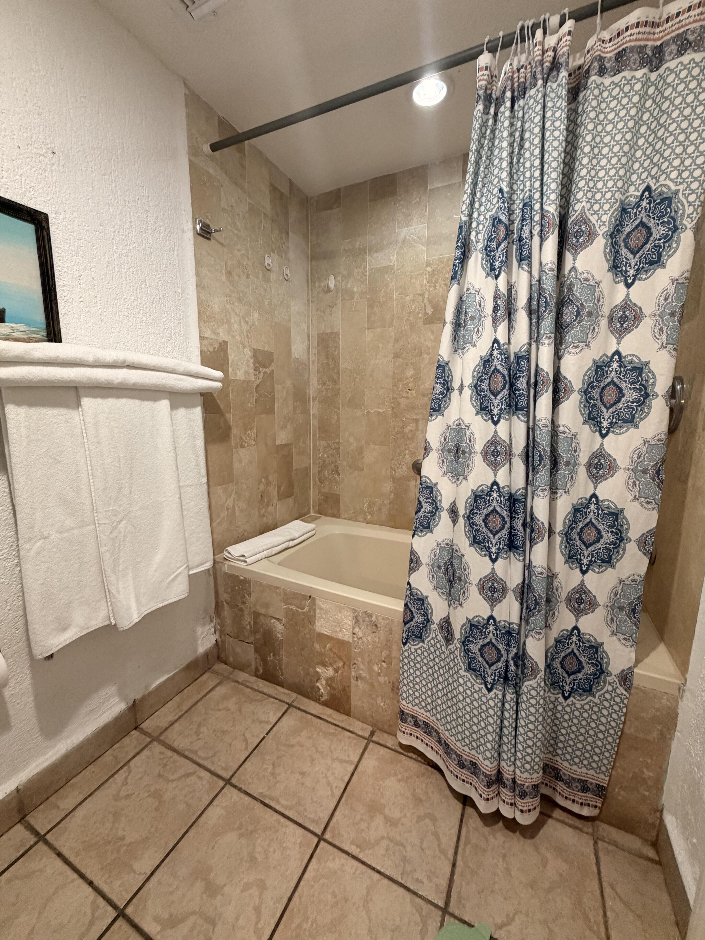 Un baño con bañera, ducha y cortina estampada.