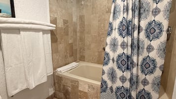 Un baño con bañera, ducha y cortina estampada.