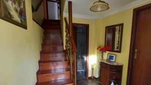 A wooden staircase leading to an upper floor, a hallway with a door, and a wall-mounted mirror. - Casa da Fonte (Peso da Regua)