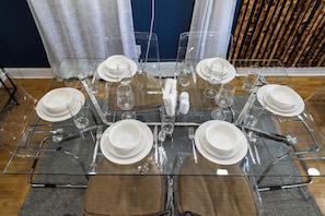 A dining table set with clear glassware and white plates, surrounded by chairs with brown cushions. - Three bedrooms | Bright living room | Free parking (Jersey City)