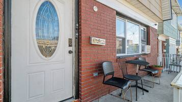 A building with a white door, a brick wall, and a window with a metal frame.