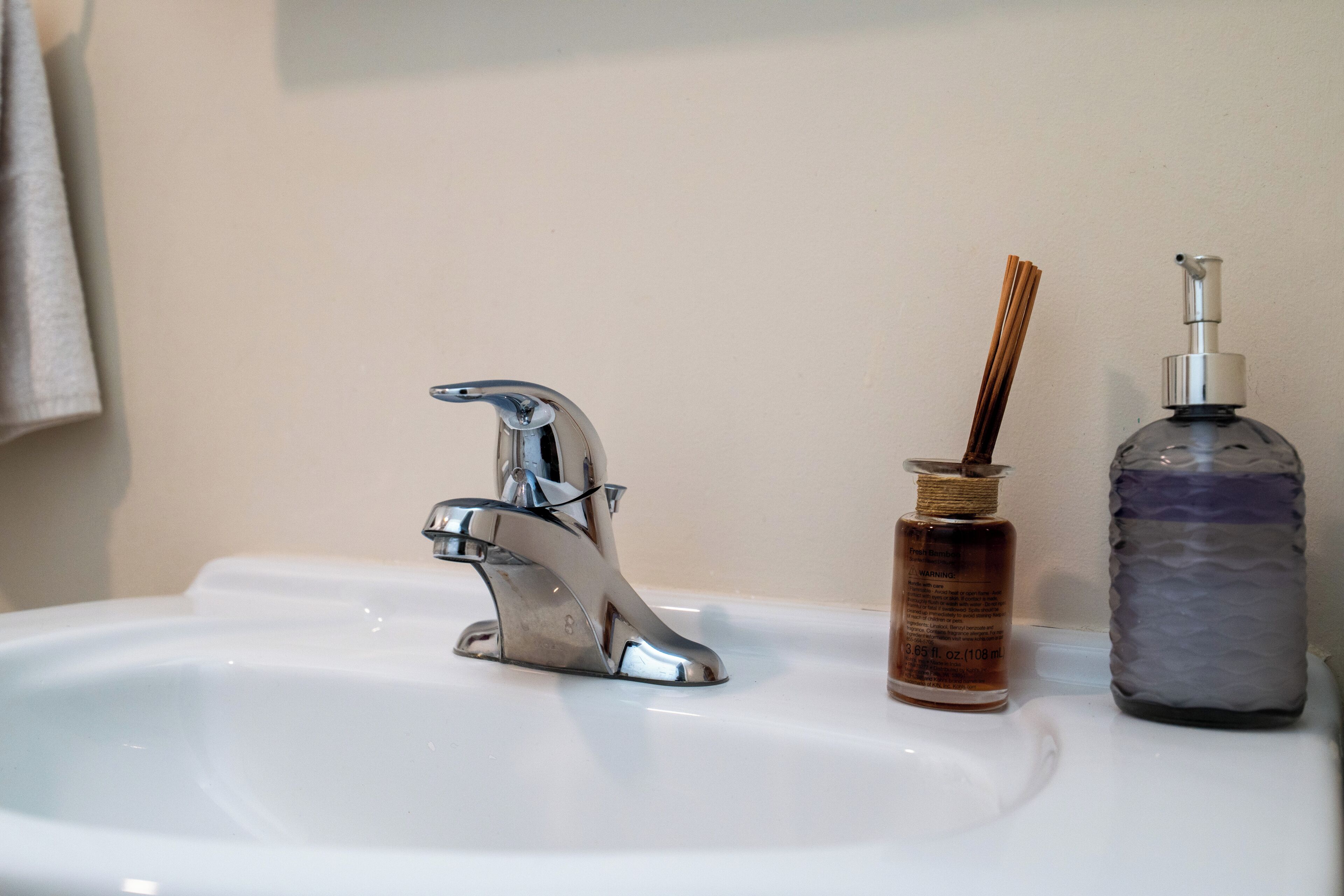 Ein Waschbecken mit einem Chrom-Wasserhahn, einer Seifenflasche und einer Handdesinfektionsmittelflasche.