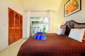 A bedroom with a large bed, a wooden headboard, a painting on the wall, and a view of greenery outside. - 4-Bedroom Villa with an Exclusive Private Pool, Sleeps 8 (playa del carmen)