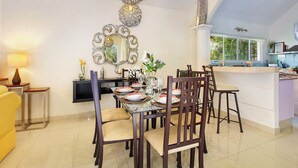 A dining area with a table set for four, surrounded by chairs, a decorative mirror, and a hanging light fixture. - 4-Bedroom Villa with an Exclusive Private Pool, Sleeps 8 (playa del carmen)