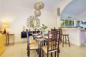 A dining area with a table set for four, surrounded by chairs, a decorative mirror, and a hanging light fixture. - 4-Bedroom Villa with an Exclusive Private Pool, Sleeps 8 (playa del carmen)