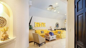A modern living room with a yellow sofa, a coffee table, and decorative items. - 4-Bedroom Villa with an Exclusive Private Pool, Sleeps 8 (playa del carmen)