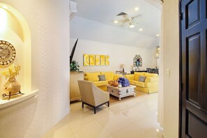 A modern living room with a yellow sofa, a coffee table, and decorative items. - 4-Bedroom Villa with an Exclusive Private Pool, Sleeps 8 (playa del carmen)