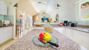 A modern kitchen with granite countertops, a glass bowl with fruits, and a coffee maker. - 4-Bedroom Villa with an Exclusive Private Pool, Sleeps 8 (playa del carmen)
