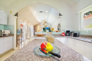 A modern kitchen with granite countertops, a glass bowl with fruits, and a coffee maker. - 4-Bedroom Villa with an Exclusive Private Pool, Sleeps 8 (playa del carmen)